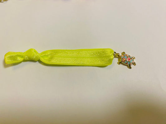 Armband aus elastischem Stoff mit einem bunten Schildkrötenanhänger.