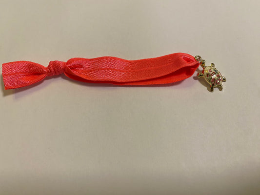 Armband aus elastischem Stoff mit einem bunten Schildkrötenanhänger.