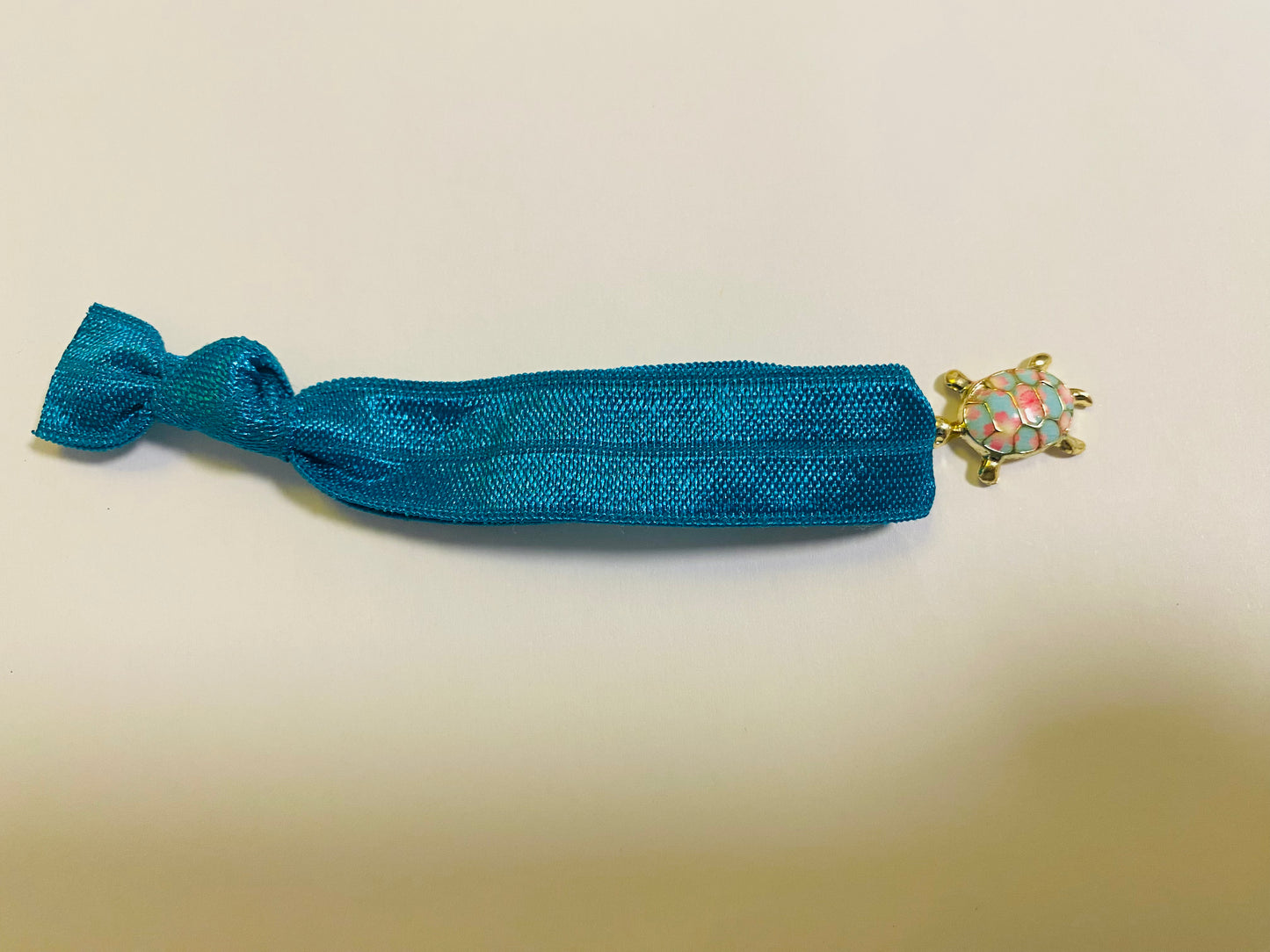 Armband aus elastischem Stoff mit einem bunten Schildkrötenanhänger